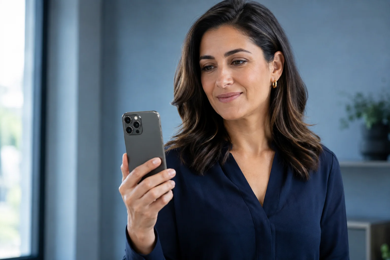 Mulher usando um celular grafite em um escritório, com a parte de trás do aparelho voltada para a câmera.